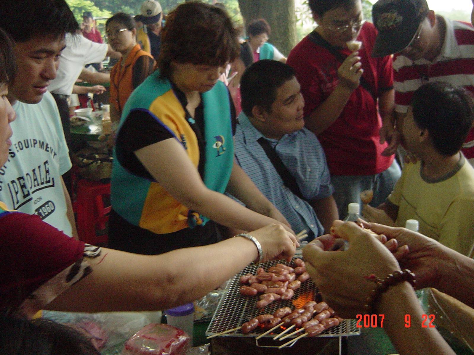 照片_志工范馨月小姐(中間居左，穿著背心者)，熱心的替大家烤香腸。